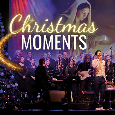 Eine Band in lila Licht neben einem geschmückten Weihnachtsbaum links, dahinter eine Leinwand mit einem Marienbild und dem Schriftzug Christmas Moments