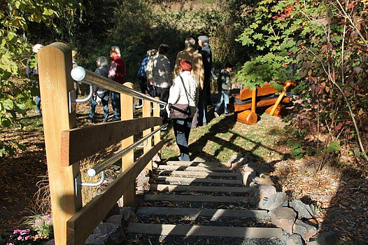 Treppenstufen und Geländer hinab zur Rodauquelle mit Festgästen