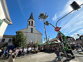 Dalles mit Kerbbaum und S. Galluskirche bei strahlendem Sonnenschein.
