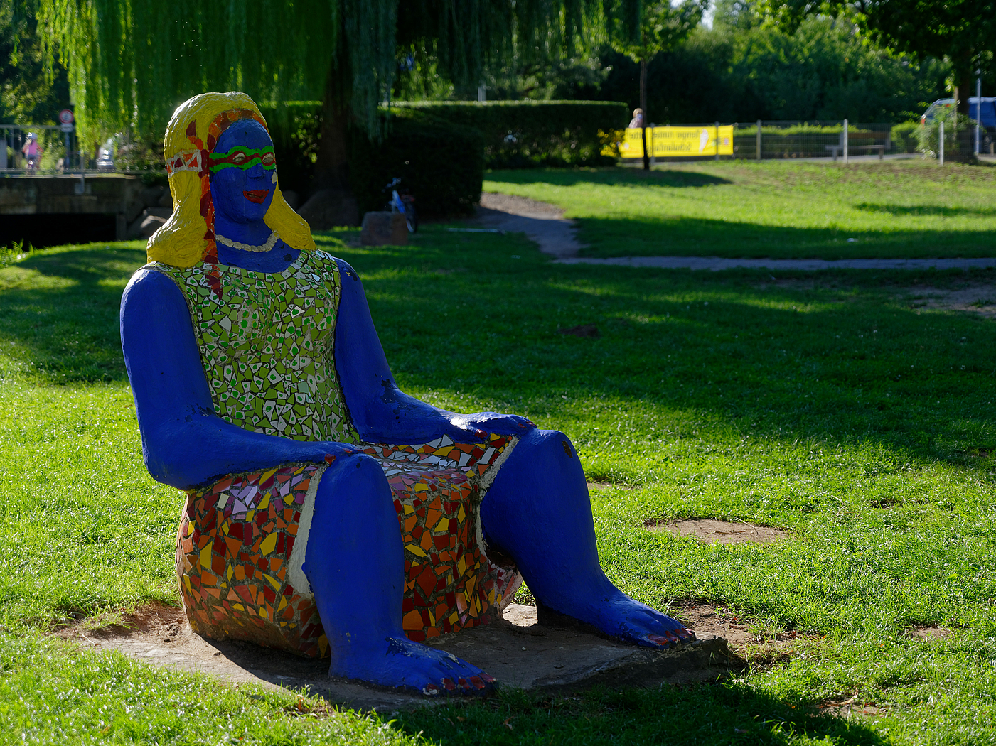 Blaue Stuhlriesin. Skulptur einer sitzenden Frau von Lou Heinrich.