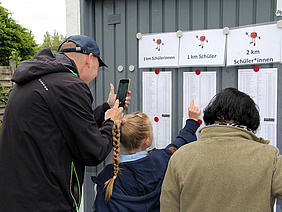 Familie schaut die Ergebnislisten der Schülerläufe an