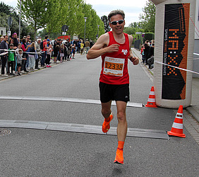 Teilnehmer im roten Oberteil läuft im Ziel ein