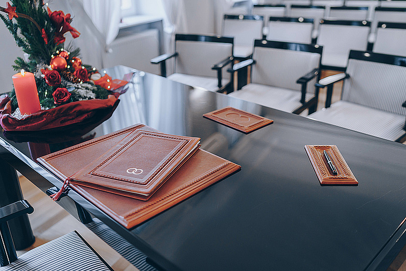Blick auf eine in braunes Leder gebundene Traumappe und Stifte auf dem festlich geschmückten Tisch, an dem das Brautpaar im Standesamt Rödermark Platz nimmt.
