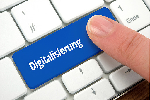 Finger drückt blaue Taste mit der Aufschrift 'Digitalisierung' auf weißer Computertastatur