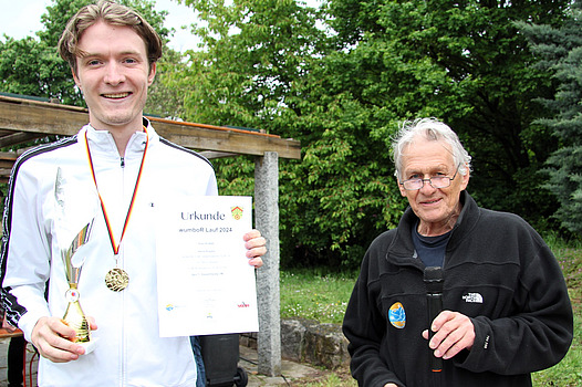 Siegerehrung für den Schnellsten, Sven Künne, der Pokl und Urkunde in Händen hält.