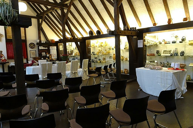 Bestuhlung im Töpfermuseum für eine Trauung, im Hintergrund die dunklen Sparren des Töpfermuseums, im Vordergrund Stuhlreihen und Stühle für das Brautpaar mit weißen Hussen.