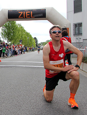 Mann kniet im Zielbereich nach erfolgreicher Teilnahme