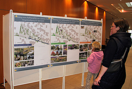 Frau und Kind betrachten Pläne der Umgestaltung an einer Pinnwand.