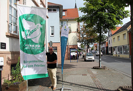 Bürgermeister Jörg Rotter mit der Flagge der Mayors for PEace 2022
